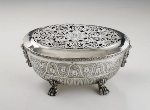 silver warmer of oval shape, standing on four paw feet, pierced lid with floral motifs