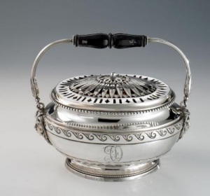 silver warmer of oval shape standing on oval beaded foot. Body engraved with monogram FO and decorative motifs, pierced lid with leaves